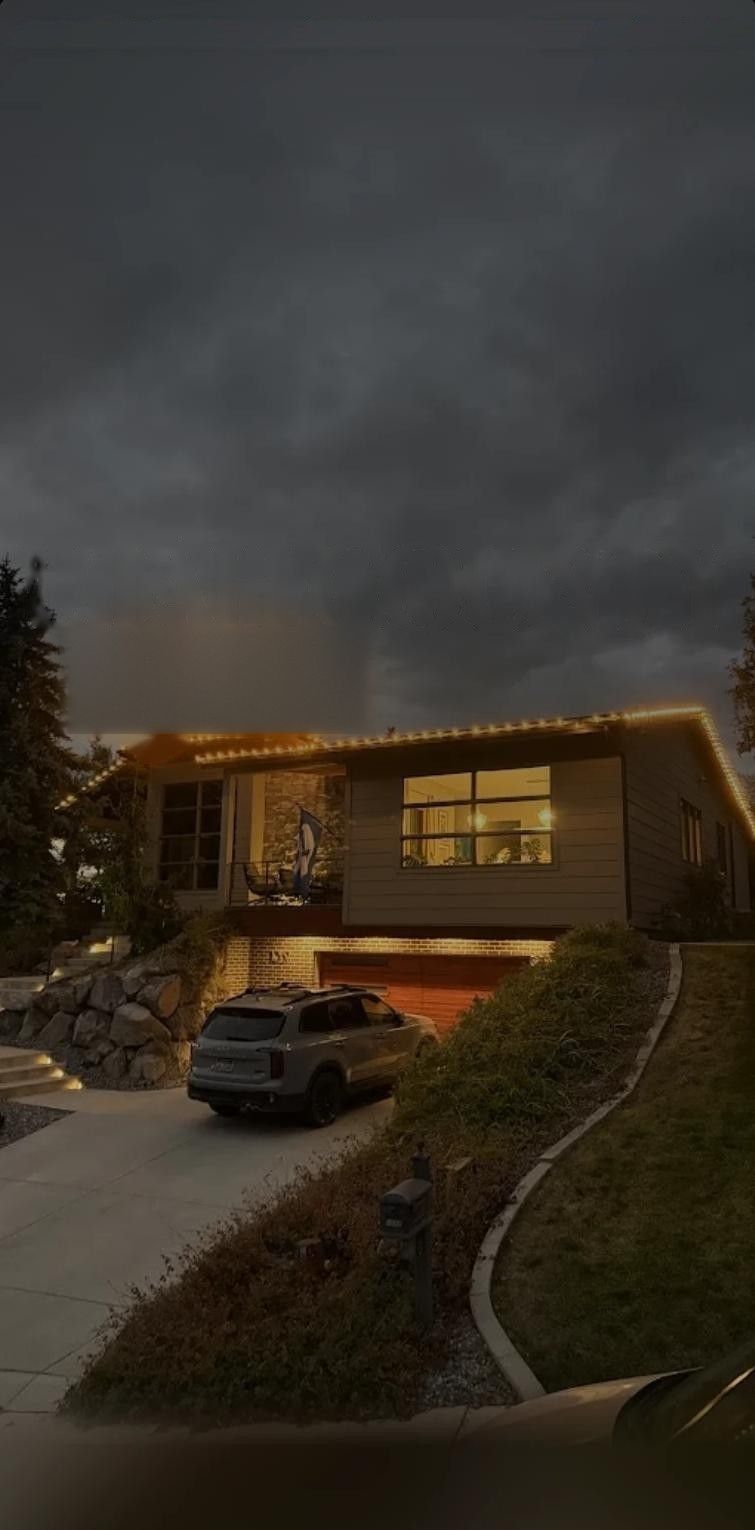 A Utah County home at dusk with warm white Christmas lights along the roofline
