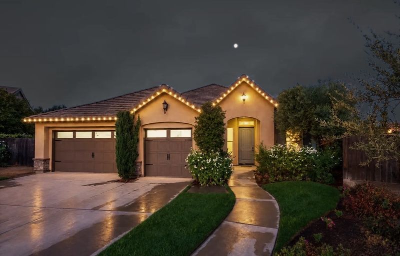 Single-story home at night with warm white lights along the roofline and gables